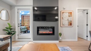 Ein modernes Wohnzimmer mit Kamin, Essbereich und Blick ins Freie.
