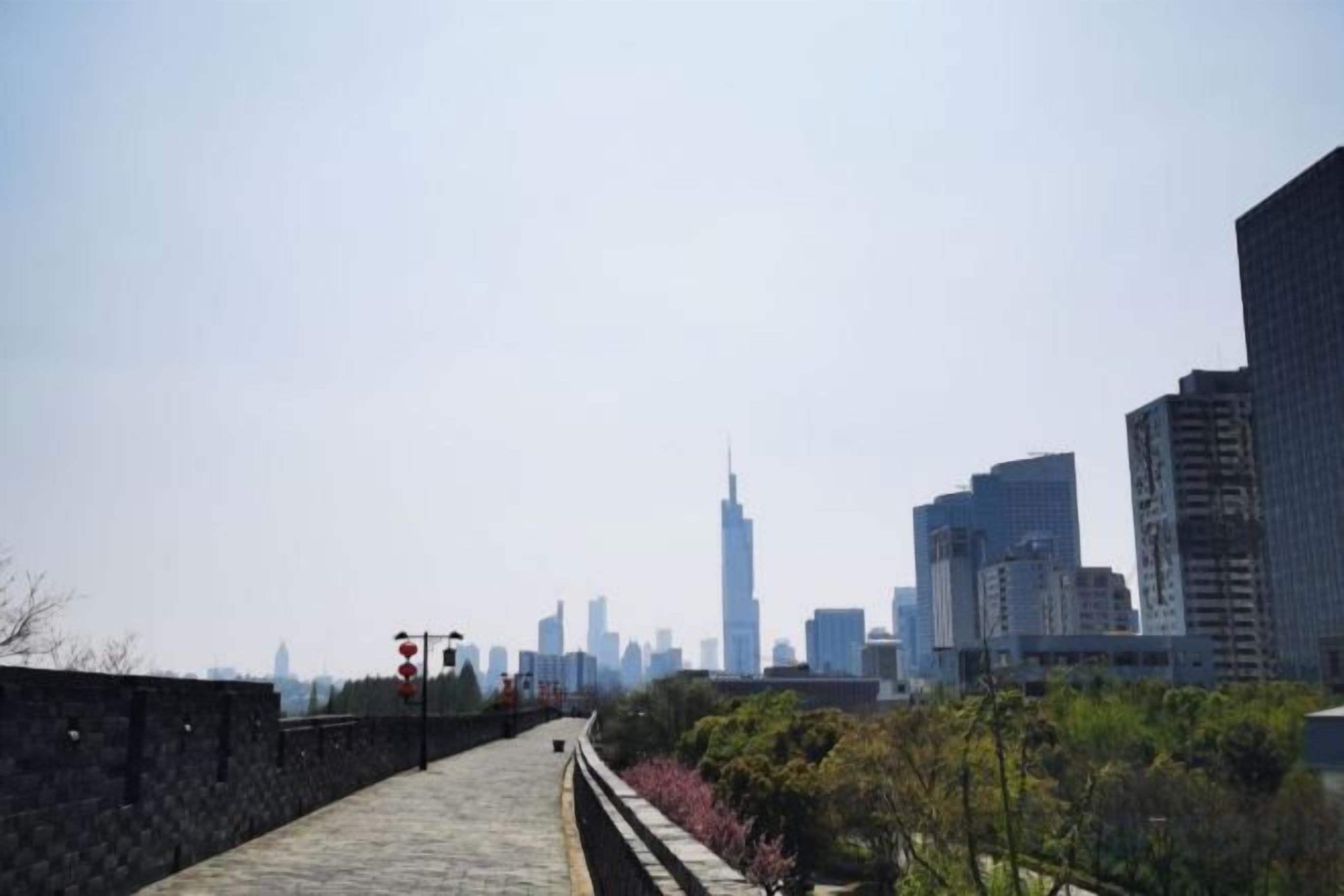 A pathway leading to a city skyline with modern buildings, including a prominent skyscraper.