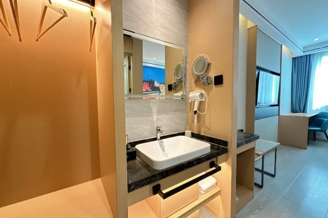 A modern bathroom with a white sink, mirrors, and a hairdryer.