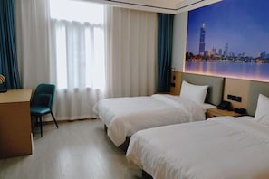 A hotel room with two beds, a desk, a chair, and a cityscape painting on the wall. - Vientiane Hengyuan Hotel (Nanjing Jianning Road Railway Station) (Nanjing)