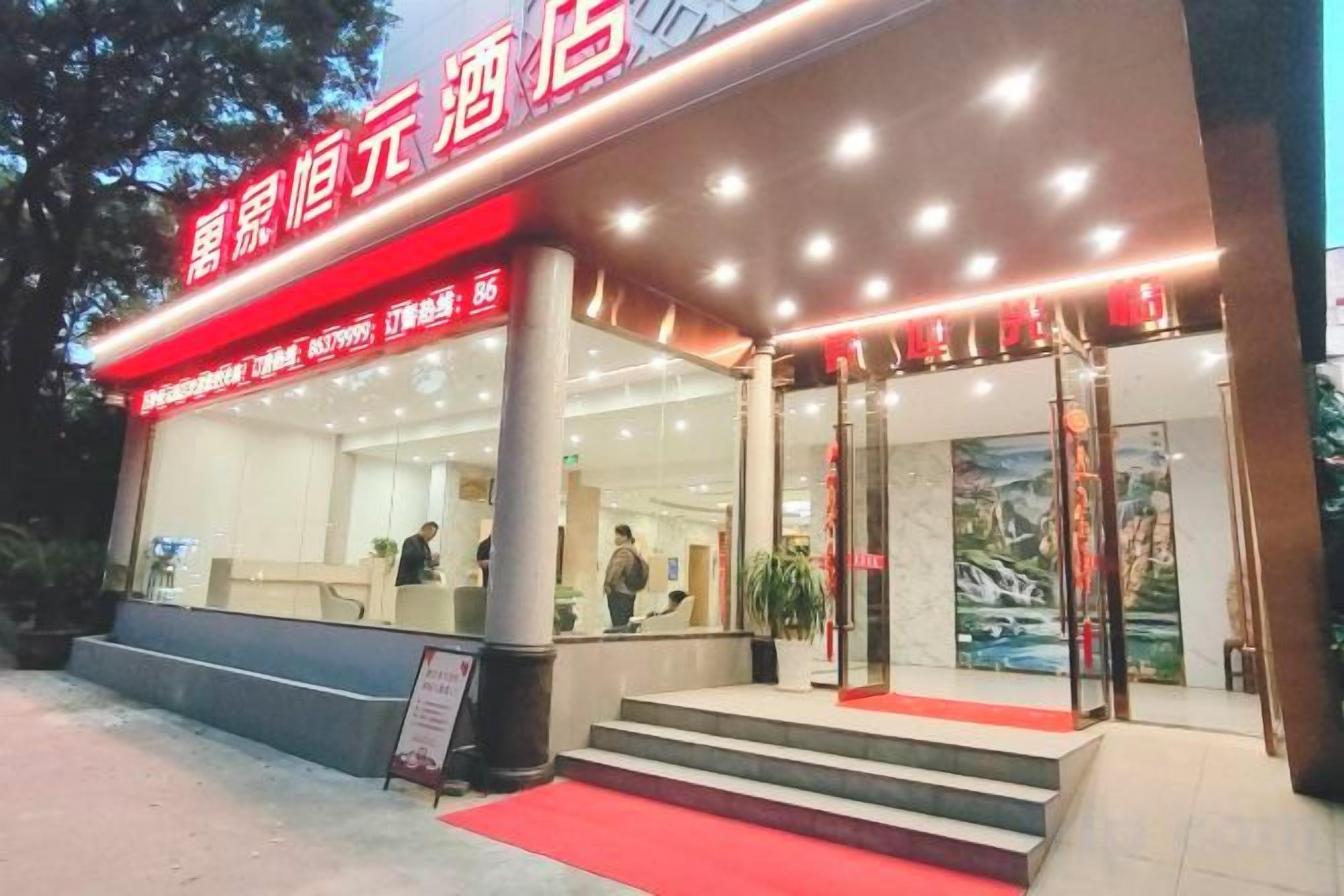 Entrada de hotel con toldo rojo, un mostrador de recepción y una escalera que conduce al acceso.
