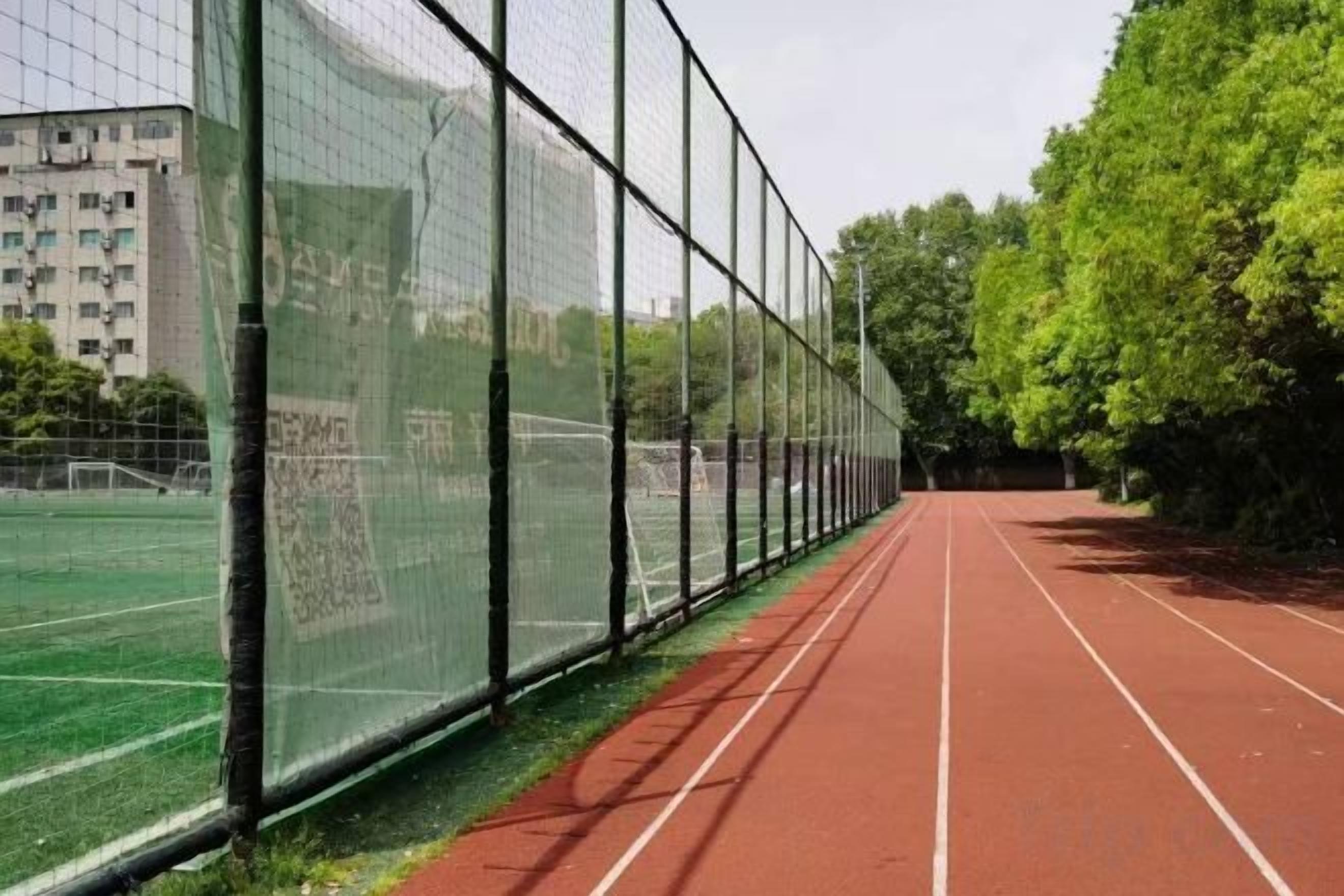 A running track with a green field and a building in the background.