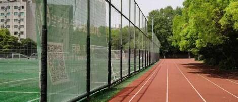 A running track with a green field and a building in the background.