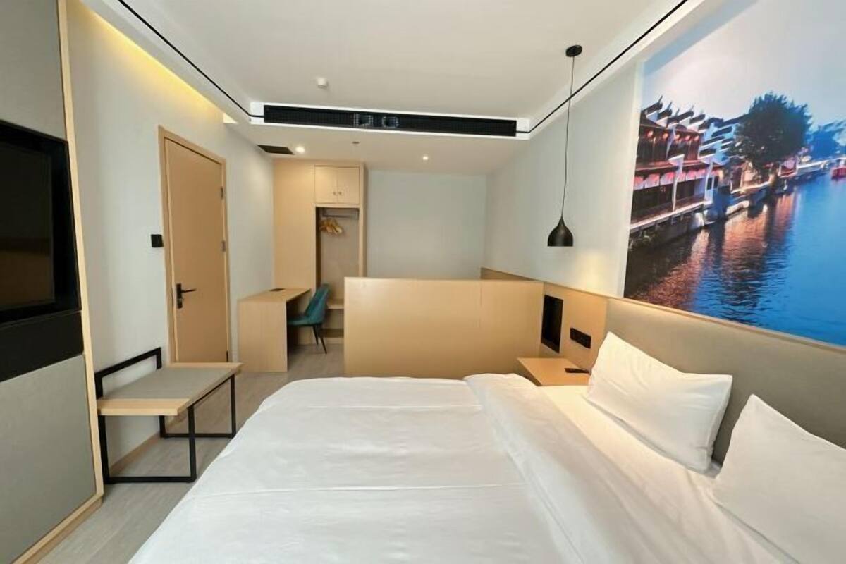 Una habitación de hotel moderna con una cama grande, un escritorio, una silla y un televisor montado en la pared.