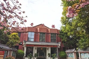 Un bâtiment en briques rouges, de style architectural chinois traditionnel, avec un toit en tuiles et une entrée centrale surmontée d’une arche décorative.