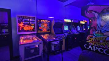 Een kamer met speelautomaten, waaronder een Street Fighter II Capcom spel, en een muurschildering van een gespierde figuur.
