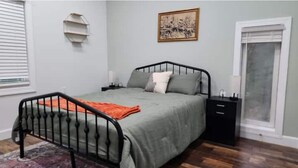 A bedroom with a bed, a nightstand, a window, and a wall-mounted shelf. - Eagle’s Landing (Lock Haven)
