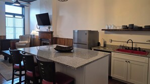 A modern kitchen with granite countertops, a built-in island, a stainless steel refrigerator, and a red sink. - The Delaney's Saloon (Vevay)