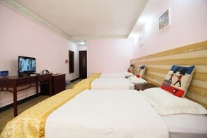 A hotel room with two beds, a desk, a television, and a wooden headboard with decorative pillows.