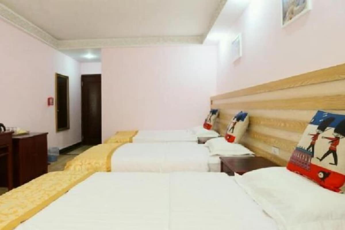 Une chambre d’hôtel avec trois lits, un bureau et une télévision.