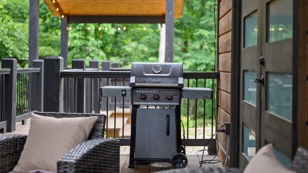 A barbecue grill on a porch with wicker furniture and a wooden pergola overhead. - Bearly Creekin' Stay for 14! (Broken Bow)