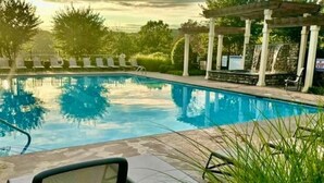 En swimmingpool med solstolar och en pergola.