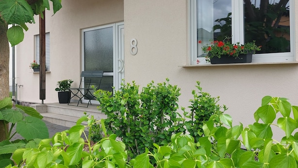 A house with a beige exterior, a black roof, and a window with a flower box.