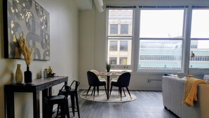 A modern living room with a dining area, large windows, and a view of a building. - Ste 713+City Views+Free Parking+Indoor Access to Skywalk (Indianapolis)