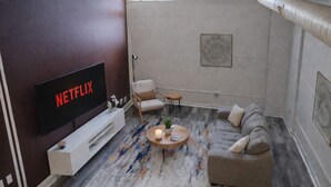 Un salon moderne avec un téléviseur à écran plat, un canapé, une table basse et un tapis à motifs.