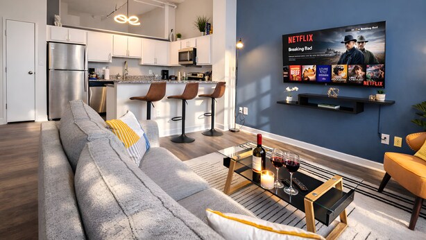 A modern living room with a grey sofa, a coffee table with wine, and a TV displaying a Netflix show. - Ste 404 Center of Downtown-Skywalk Access to Convention Center+Free Parking (Indianapolis)