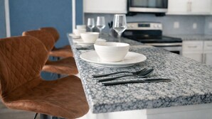 A kitchen with a granite countertop, white cabinets, a microwave, and a stove.