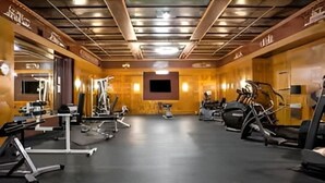 A gym with exercise equipment, a flat-screen TV, and a wooden interior.