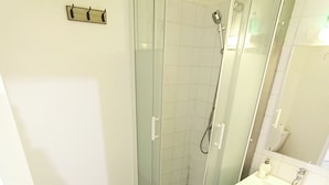 Une salle de bain avec douche, toilettes et lavabo.
