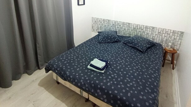 Une chambre à coucher avec un lit, un petit tabouret et un rideau.