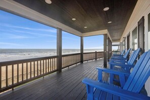 A covered deck with blue chairs and a view of the beach. - Shore Thing - Beach Front - Sleeps 22 (Port Bolivar)