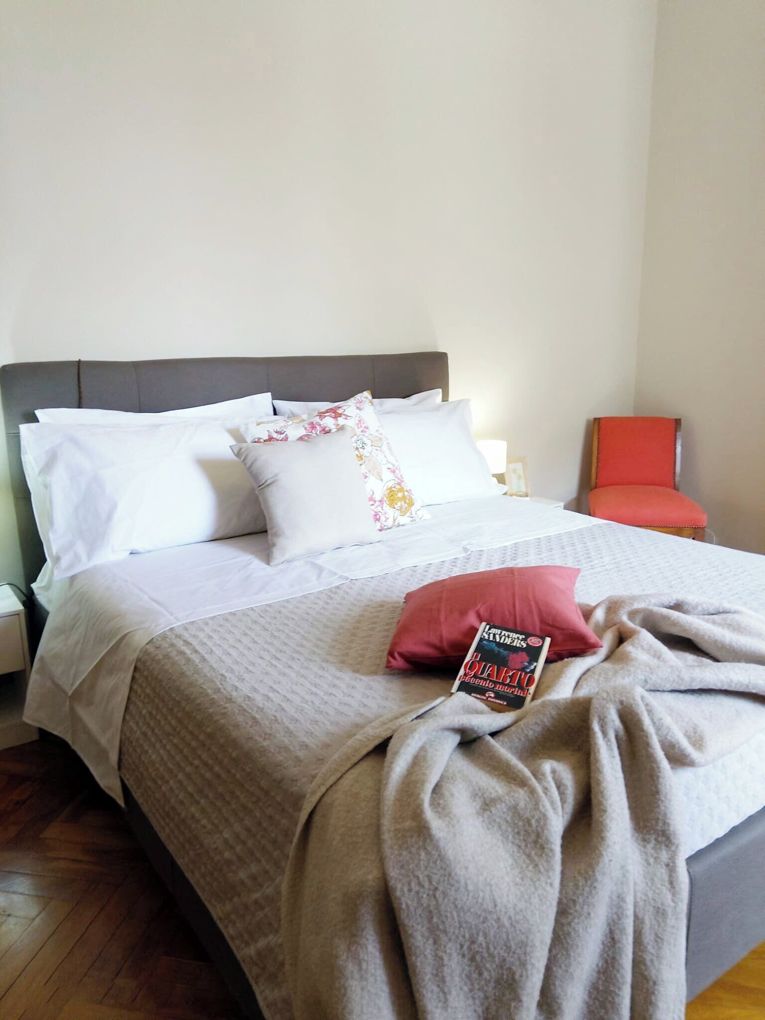 A neatly made bed with a patterned bedspread, pillows, and a book on it.