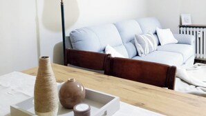 A modern living room with a wooden coffee table, a floor lamp, and a sofa with cushions.