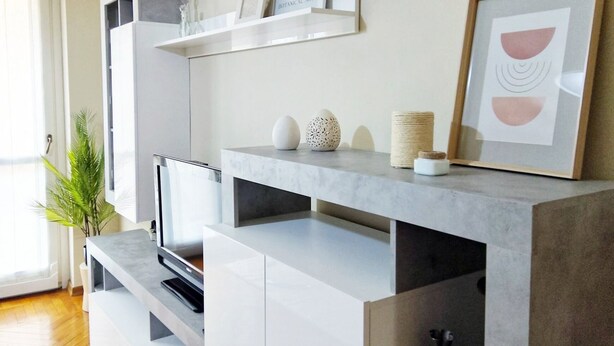 A modern living room with a grey entertainment unit, a flat-screen TV, and decorative items.
