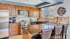 A modern kitchen with wooden cabinets, stainless steel appliances, and a large island with bar stools.
