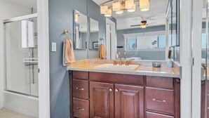 A modern bathroom with a large mirror, a double sink vanity, and a shower area.