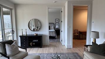 A spacious living room with a large mirror, a dark wooden cabinet, and a beige sofa.