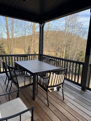 Eine überdachte Terrasse mit einem rechteckigen Tisch und Stühlen, umgeben von einem Holgitter.