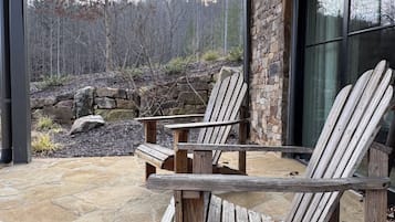 A stone patio with Adirondack chairs and a stone wall.