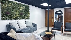 A modern living room with a dark blue sofa, a glass coffee table, and a green wall with a vertical garden.