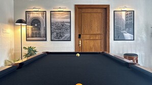 A pool table with balls, a wooden door, and framed pictures on the wall.