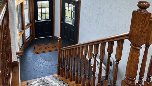 A wooden staircase with a black door and a doormat.