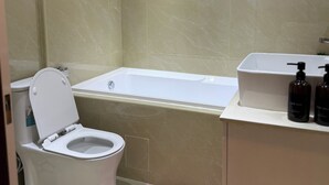Un baño moderno con inodoro, bañera y lavamanos con artículos de aseo.