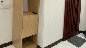 Un armario de madera con espacio para colgar, un cajón pequeño y un estante.