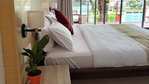 Un dormitorio moderno con una cama grande, una mesita de noche con lámpara y una planta en maceta.