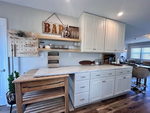 Una cocina con armarios blancos, encimera de madera y un letrero colgante que dice 'BAPT'.