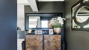 A modern interior with a herringbone-patterned wooden cabinet, a large mirror, and a decorative wall piece.