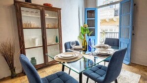 A dining area with a glass table, blue upholstered chairs, and a cabinet with glass doors.
