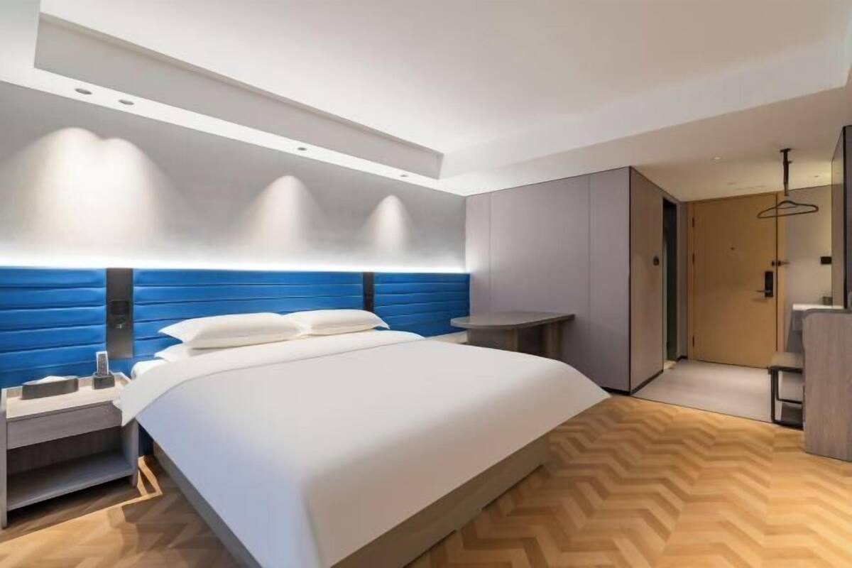 Une chambre d’hôtel moderne avec un grand lit, une table de chevet, un bureau et une armoire.