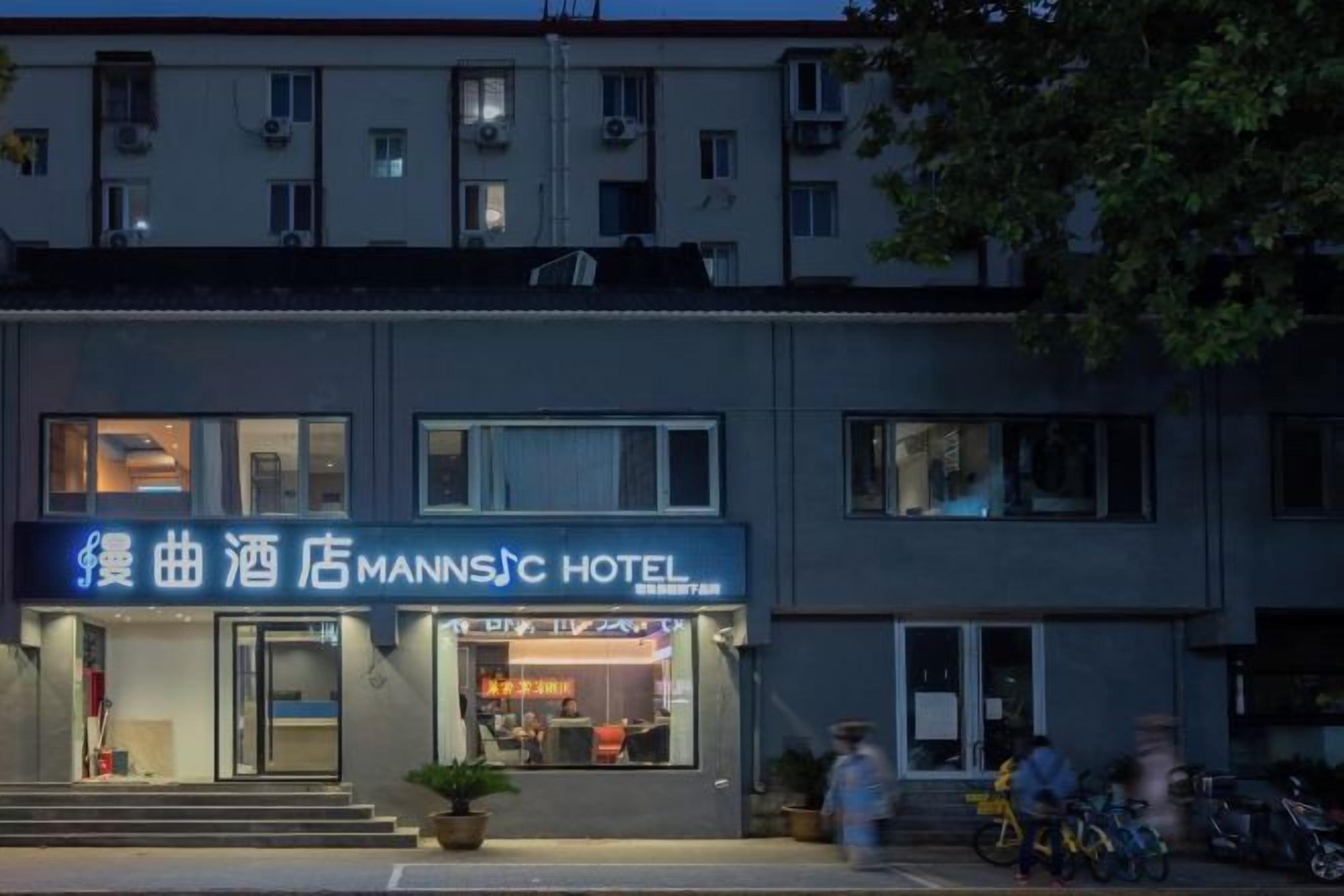 A hotel with a signboard, a visible entrance, and a few people outside.