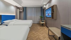 Ein Hotelzimmer mit zwei Betten, einem Schreibtisch, einem Stuhl, einem Fernseher und einem Fenster mit Vorhängen.