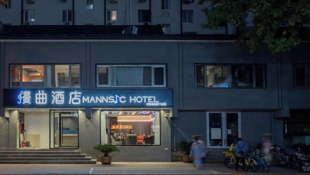 Ein Hotel mit Schilder in einer fremden Sprache, einem gut sichtbaren Eingang und einem Parkplatz mit Fahrrädern.