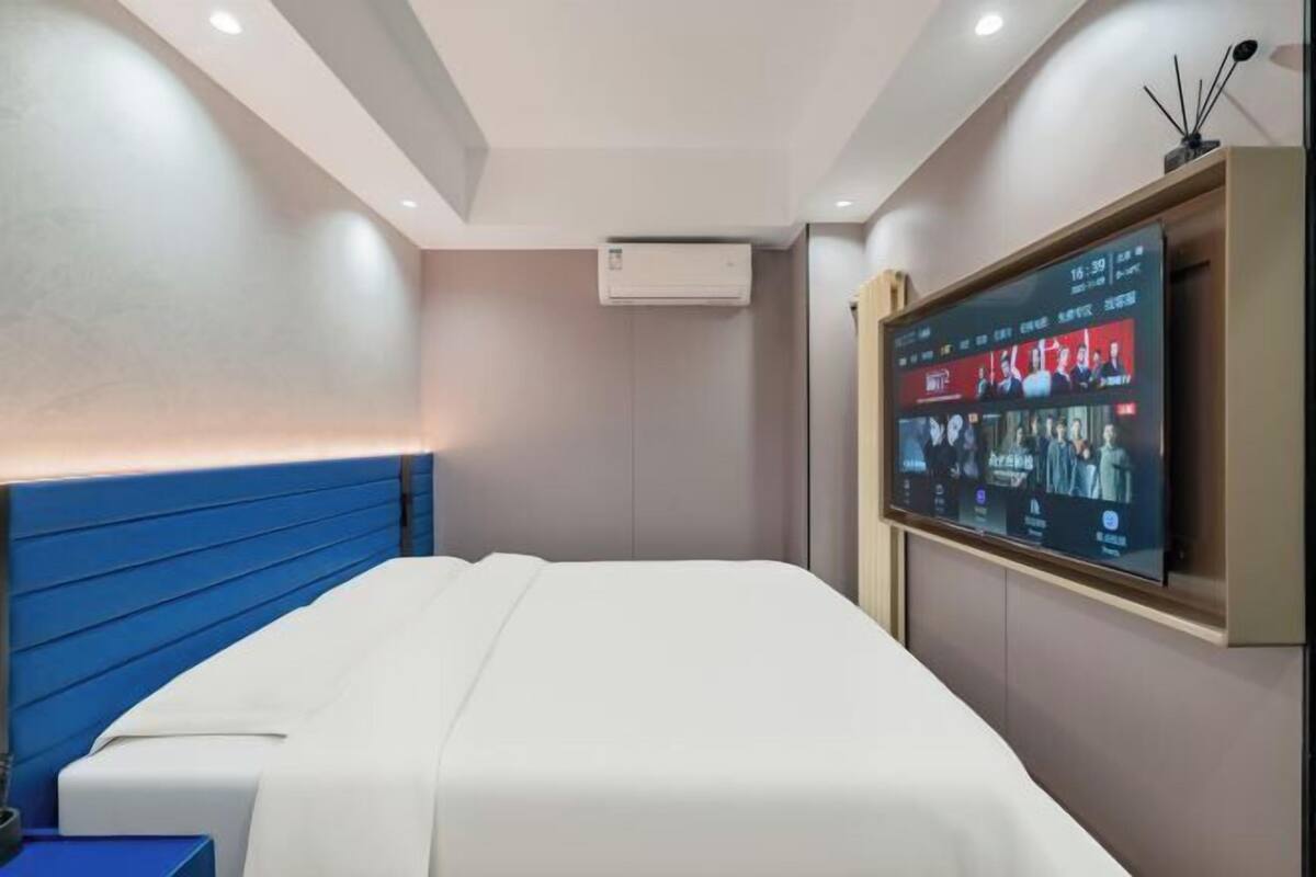 Une chambre d’hôtel moderne équipée d’un lit, d’un téléviseur à écran plat fixé au mur et d’un système de climatisation.
