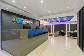 Uma área de recepção moderna, com balcão, espaço para sentar e teto com iluminação embutida.