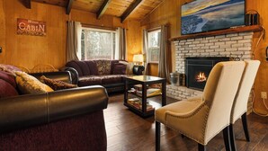 A cozy cabin interior with a fireplace, wooden walls, and a sofa.