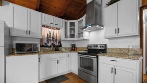 A modern kitchen with white cabinets, stainless steel appliances, and a granite countertop.